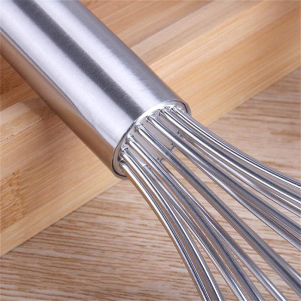 Metallic whisk on a wooden surface