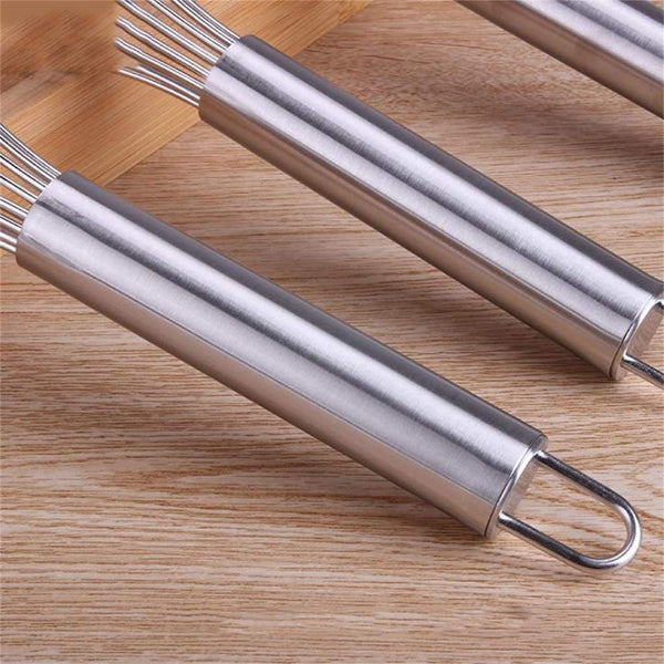 Two metal whisks on a wooden surface
