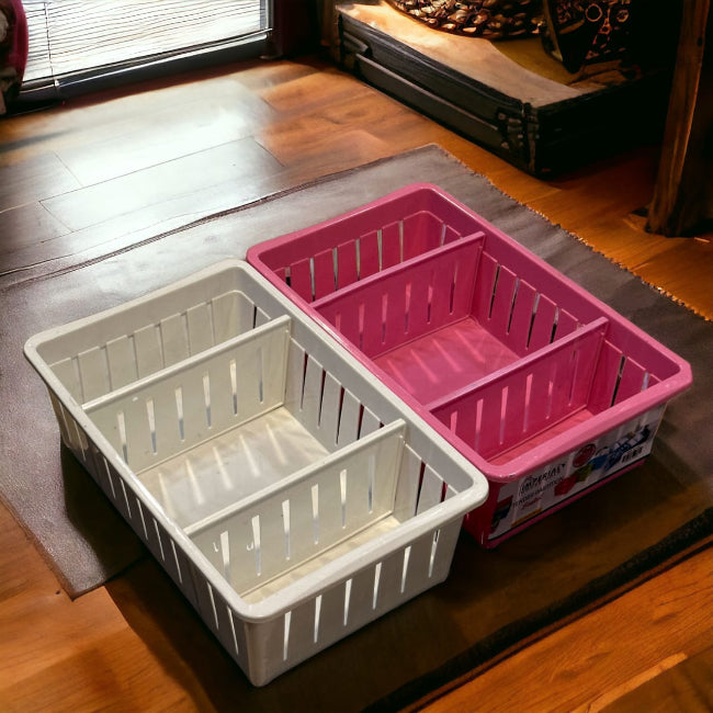 Close-up of a white plastic multi-purpose storage basket with three adjustable compartments, holding kitchen utensils and small desk supplies.