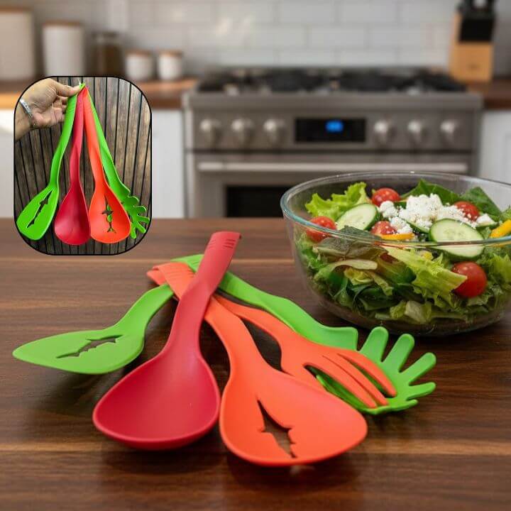 Colorful salad servers on a kitchen counter with a bowl of salad in the background.
