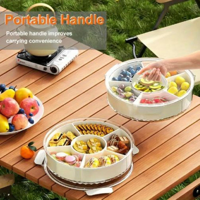 Close-up of a white multi-compartment rotating snack organizer tray with a lid, open and filled with colorful candies, nuts, and dried fruit.