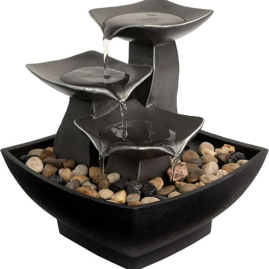 Black tiered water fountain with pebbles on a white background