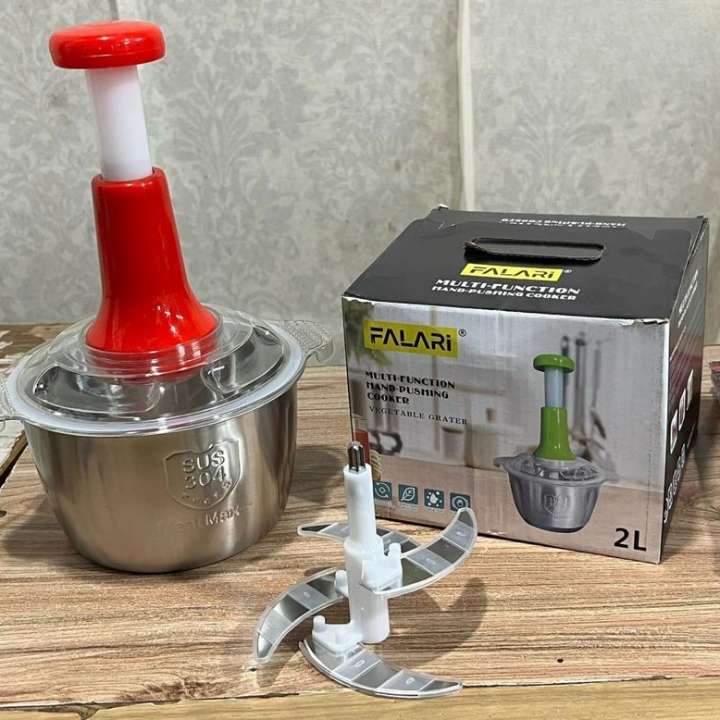 Multifunctional food processor with red top and metal base, next to its packaging box on a wooden surface.