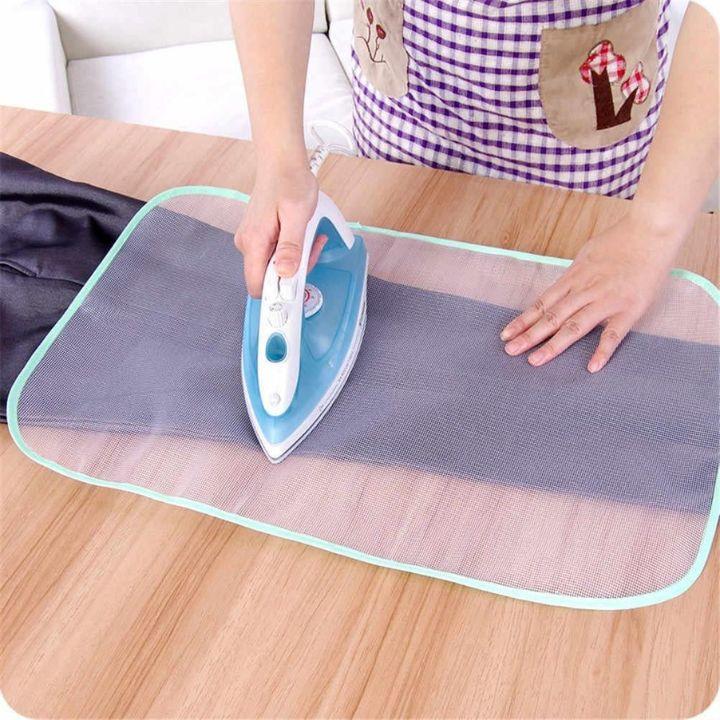 Person ironing fabric on a mesh ironing board with a checkered apron.