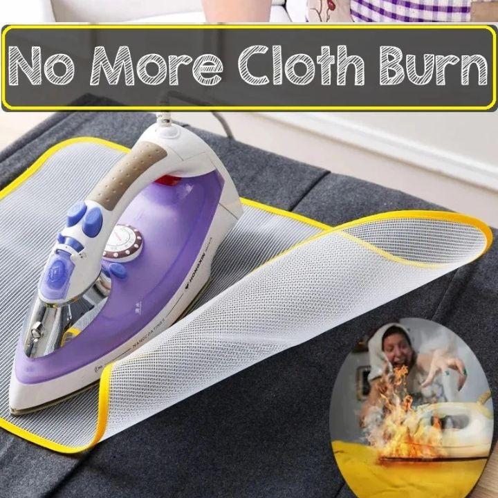 A white and purple ironing board protector sheet with a yellow trim is shown under a purple and white steam iron on a dark gray fabric surface. A black banner at the top reads 'No More Cloth Burn' and a circular inset shows a person reacting to a burning cloth.