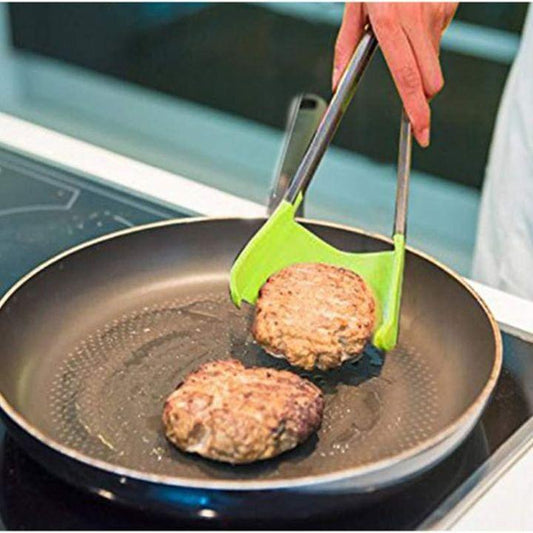 A hand uses metal tongs with bright green silicone tips to lift a burger patty from a black frying pan on an induction cooktop.