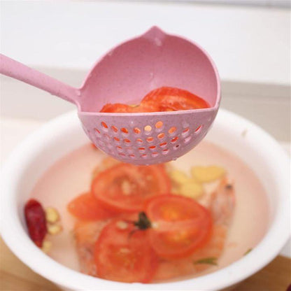 A pink plastic slotted ladle holding sliced red tomatoes above a white bowl of water with ingredients, shown in a kitchen-like setting.