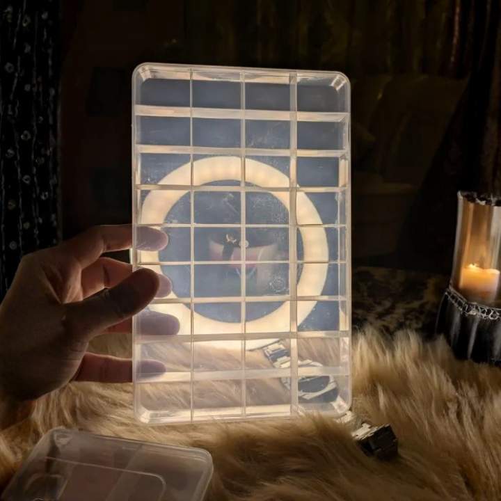Clear plastic organizer with grid pattern held by a hand on a textured surface. AABA MALL 