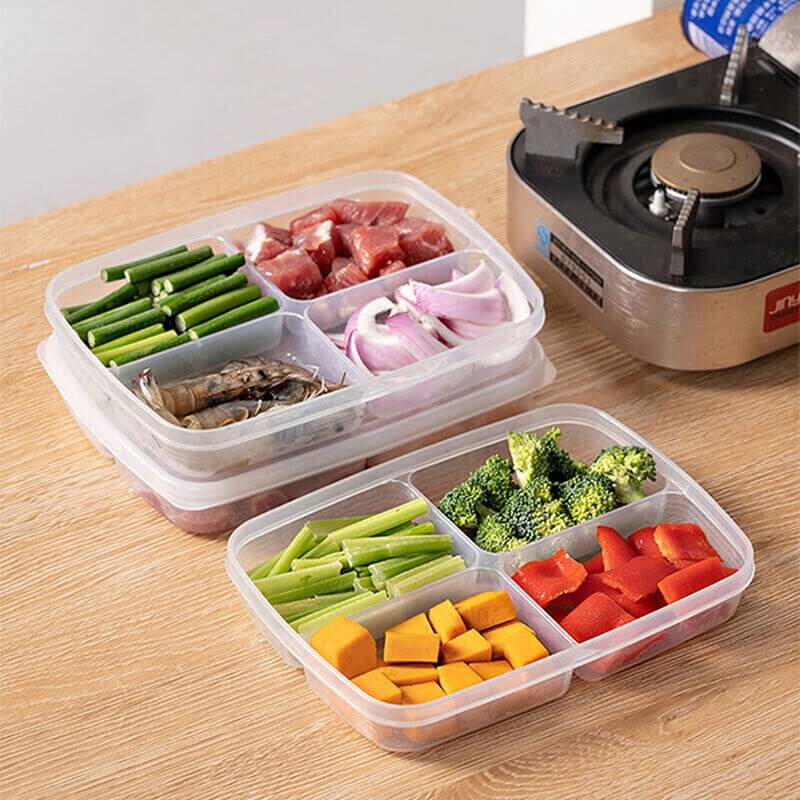 Two compartment food containers with compartments of vegetables and meat on a wooden table.