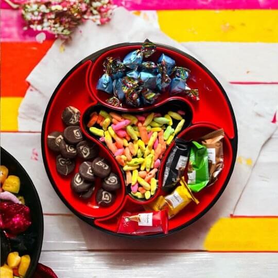 Assorted candies in a red tray on a colorful striped background
