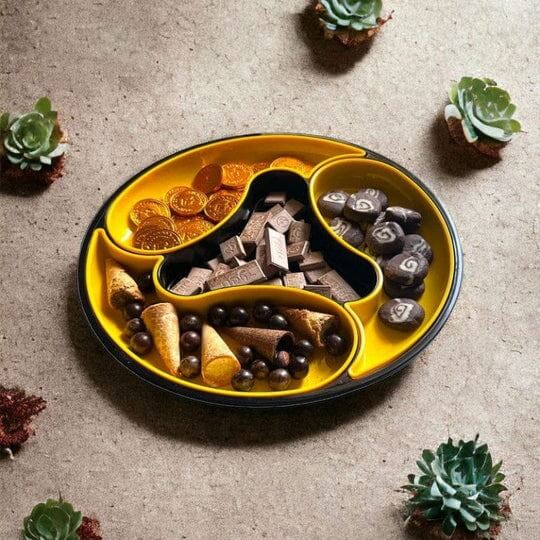 Yellow pet treat dish with compartments filled with various treats on a textured surface with succulents.