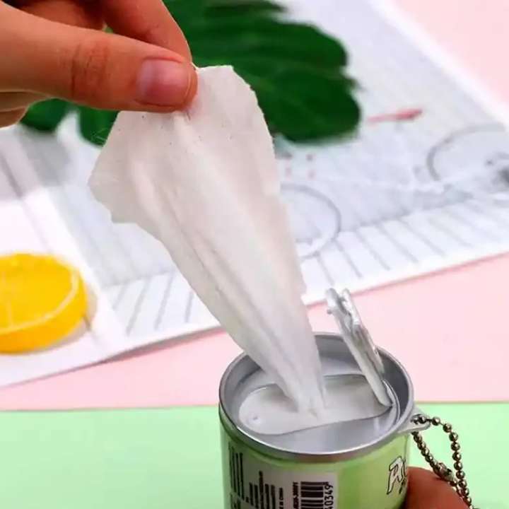 Hand using a white paper towel to clean a can, with a colorful background