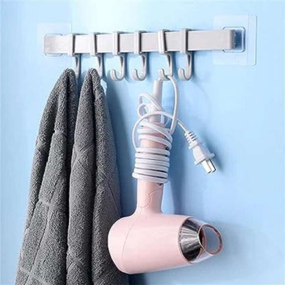 Hair dryer and towel hanging on a wall-mounted hook rack against a light blue background