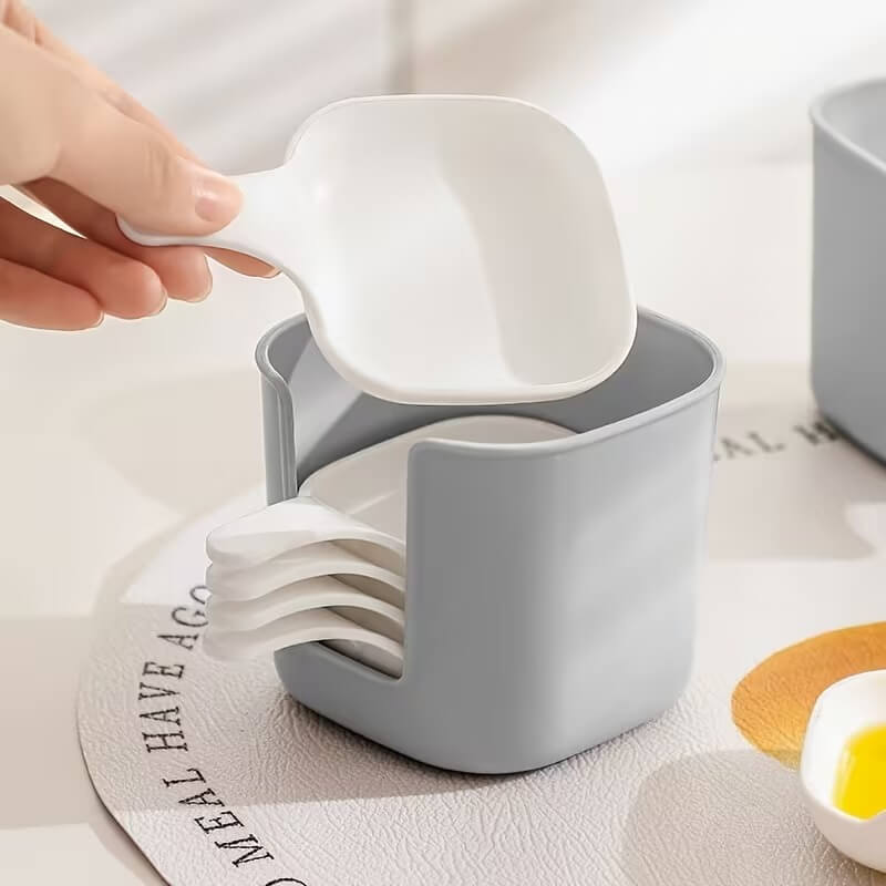 Gray container with white spoon holder and a hand holding a white spoon.