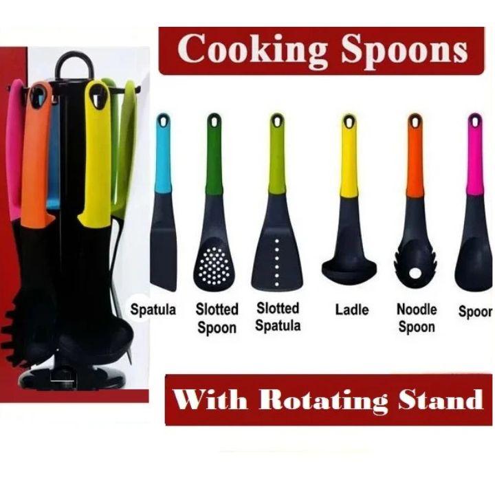 A set of eight cooking utensils with colorful handles and black heads, shown with a rotating stand. The utensils include spatula, slotted spoon, slotted spatula, ladle, noodle spoon, and spork, with text labels identifying each piece.