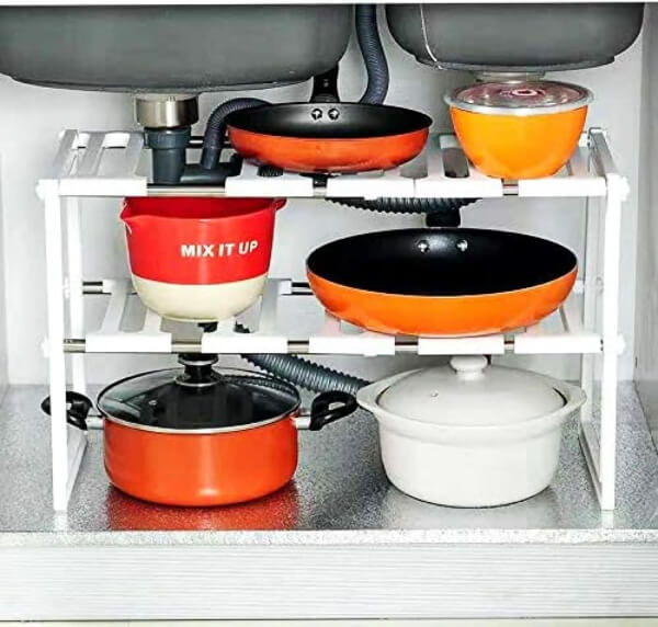 Kitchen storage rack under a sink with pots, pans, and bowls.