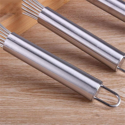 Two metal whisks on a wooden surface