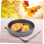 Gray round baking pan with a pastry and fruit on a wooden surface with autumn leaves in the background.