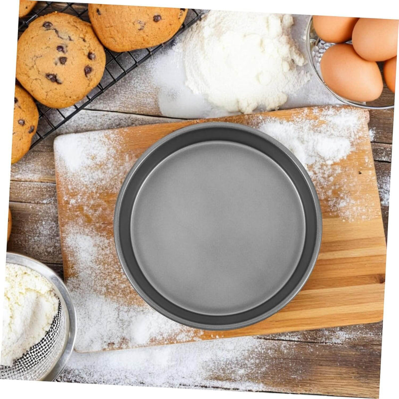 Gray round cake pan on a wooden cutting board with baking ingredients in the background