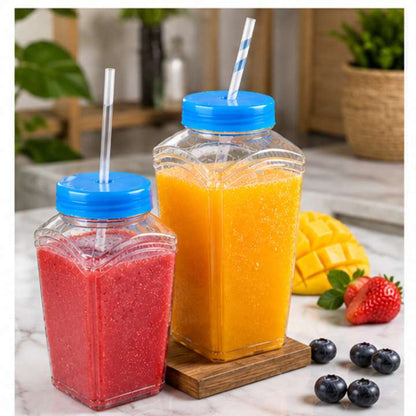Two square jars with blue lids and straws, one filled with red juice and the other with orange juice, on a marble surface with fruits.