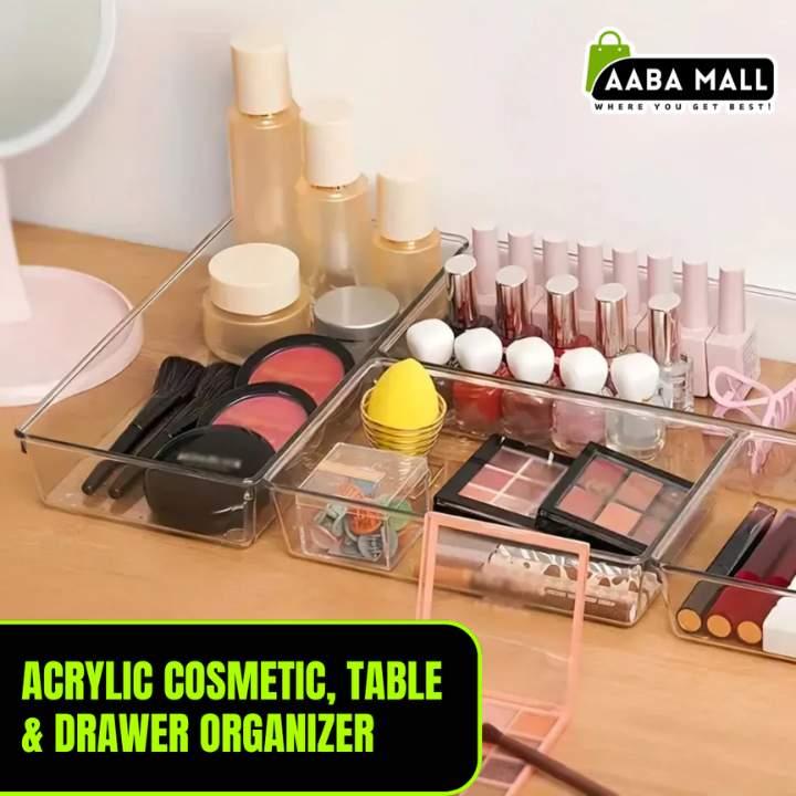 Acrylic cosmetic organizer with makeup items on a table, branded 'Aaba Mall'.