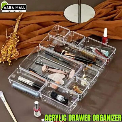 Clear acrylic drawer organizer with makeup items on a brown surface, featuring AABA MALL branding.