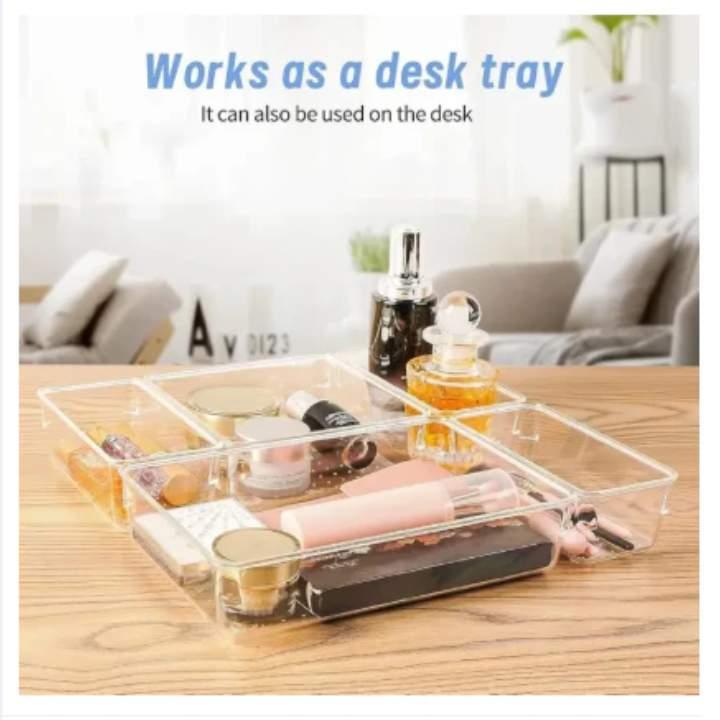 Clear plastic tray with compartments on a desk, containing small items.