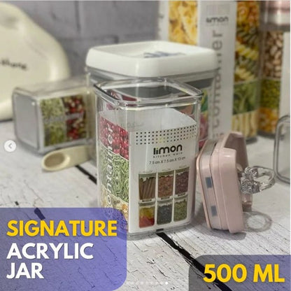 Acrylic jar with a lid on a table, surrounded by kitchen items.