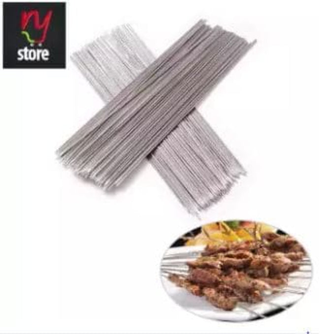 A close-up shot of a set of 6 flat, 17-inch stainless steel BBQ skewers resting on a wooden picnic table, suitable for shish kabobs and grilling.