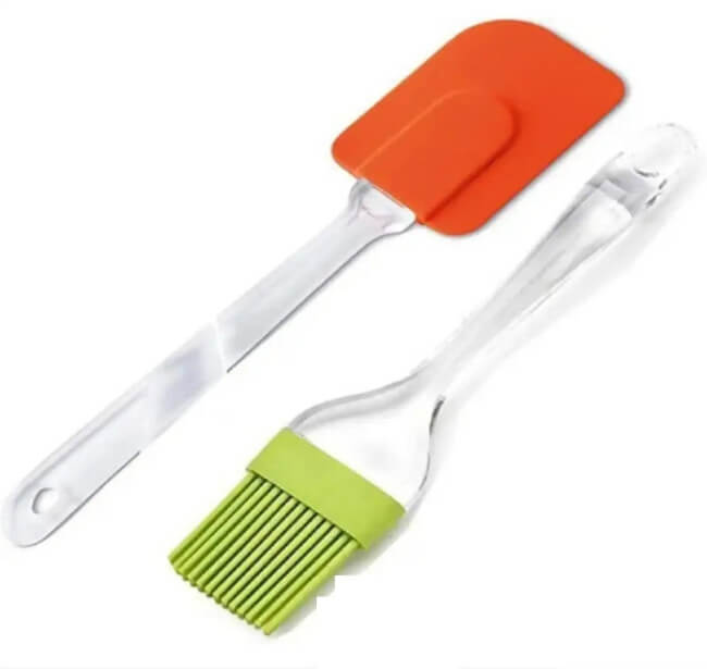 Set of two kitchen utensils with orange spatula and green brush on a white background