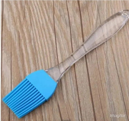 Set of 2 mini silicone kitchen tools (spatula and pastry brush) in blue, shown scraping the remnants of cake batter out of a small mixing bowl, illustrating the compact size.