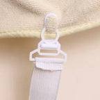 Close-up of a white curtain tieback clip on beige fabric.