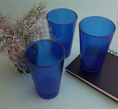 Image of six blue 300ML food-grade plastic tumblers with a vertical ribbed pattern, shown filled with ice and water on a sunny outdoor table.
