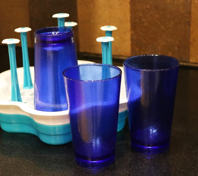 Image of six blue 300ML food-grade plastic tumblers with a vertical ribbed pattern, shown filled with ice and water on a sunny outdoor table.