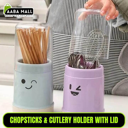 Two containers with smiley face designs, one holding chopsticks and the other cutlery, on a kitchen counter.