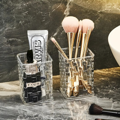 Clear acrylic makeup organizer with brushes and skincare products on a marble surface