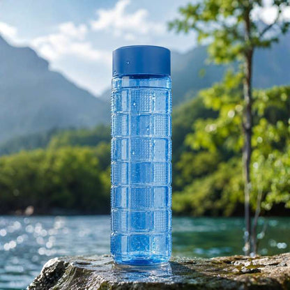 Blue water bottle on a rock with a scenic background of mountains and trees.