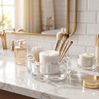 Cosmetic setup on a marble counter with brushes, cotton pads, and a perfume bottle.