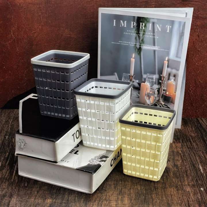 Three woven baskets in gray, white, and yellow on a wooden surface with a magazine titled 'Imprint' in the background.  AABA MALL 