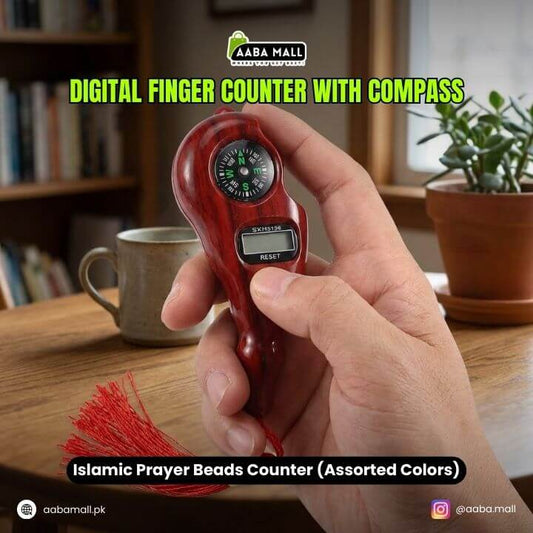Digital finger counter with compass held in a hand, with a blurred indoor background.