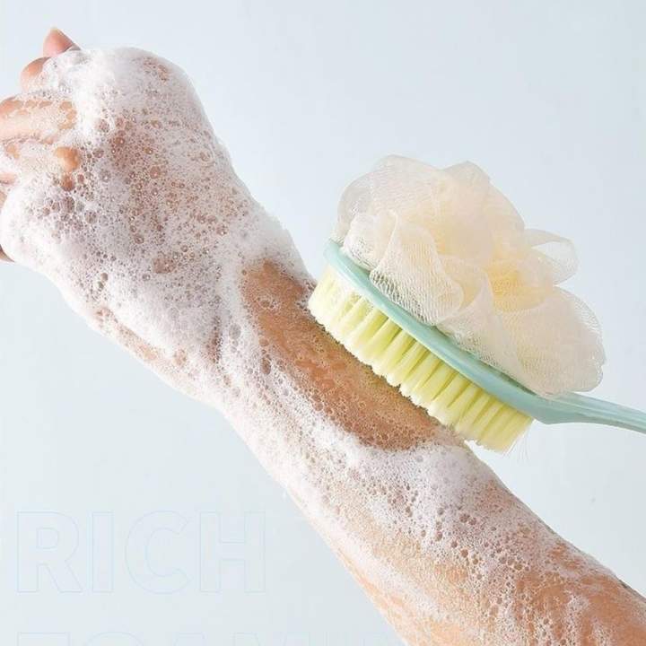 Hand using a scrub brush with soap suds on a light background