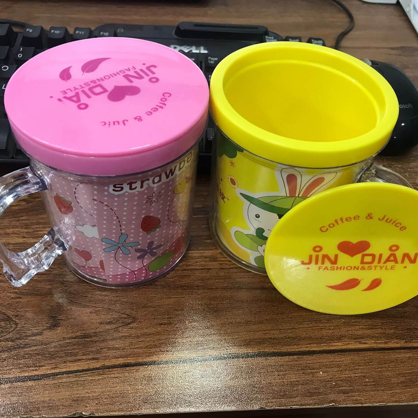 Two colorful cups with lids on a wooden surface, featuring the brand 'Jin Dian'.