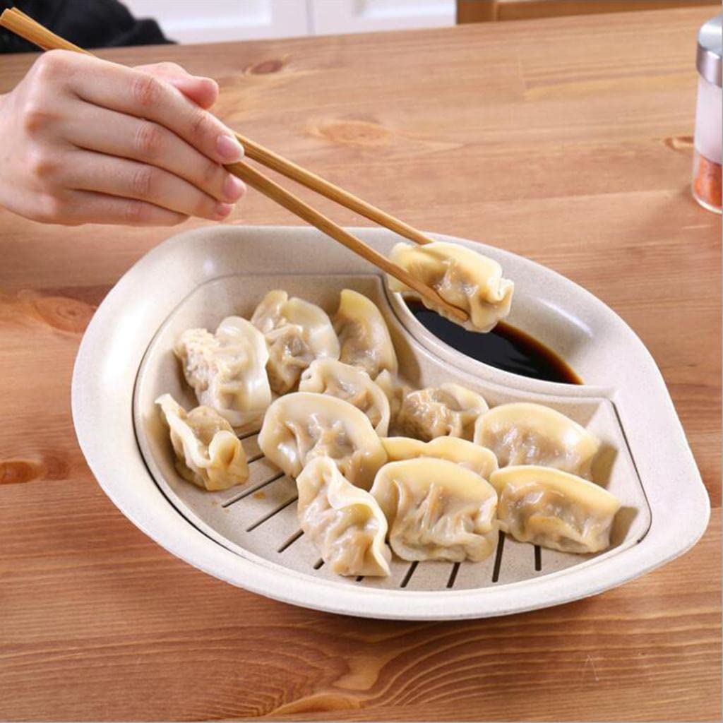 Dumplings on a white tray with a hand using chopsticks to pick up a dumpling.