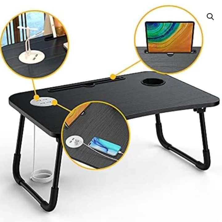 Black folding laptop desk with cup holder and power outlet on a white background