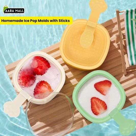 Three silicone ice pop molds with sticks are shown on a wooden tray over a pool-like blue background. One mold is open and contains strawberry ice pops, one is closed and yellow, and one is green with a lid.
