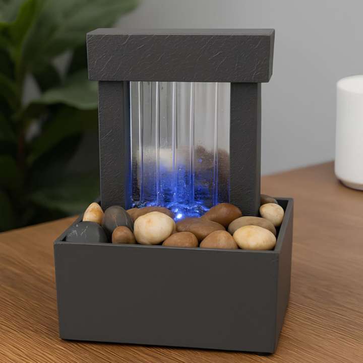 Small indoor fountain with rocks and LED lights on a wooden surface
