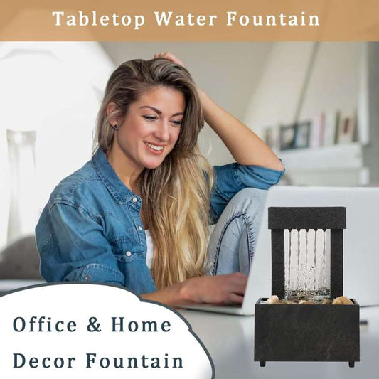 Woman using a laptop with a tabletop water fountain in front of her