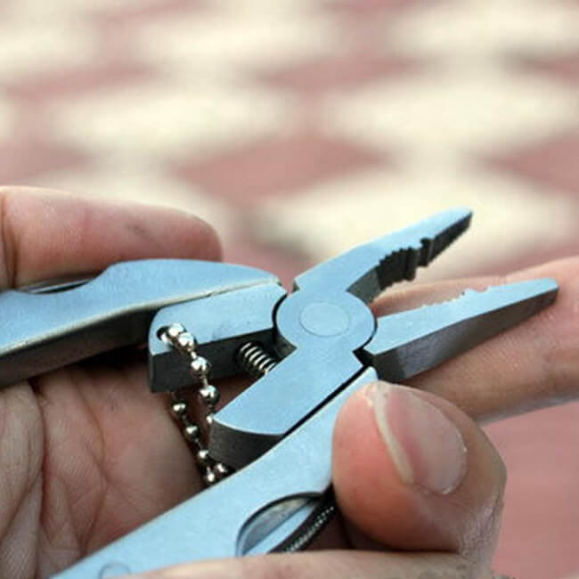 Multitool pliers being held in a hand with a blurred background