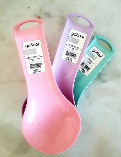 Three plastic measuring spoons in pink, purple, and teal, each with a white paper label showing the brand 'goñdol' and barcode, arranged on a light marble-like surface.
