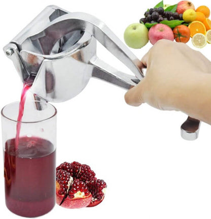 Hand using a manual juicer to extract juice from fruits and vegetables, with a glass of juice and pomegranate on a white background.